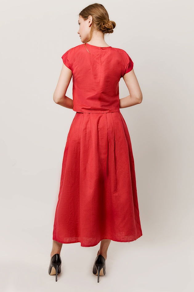 Model in cap-sleeve top in a deep-red color and long skirt back view
