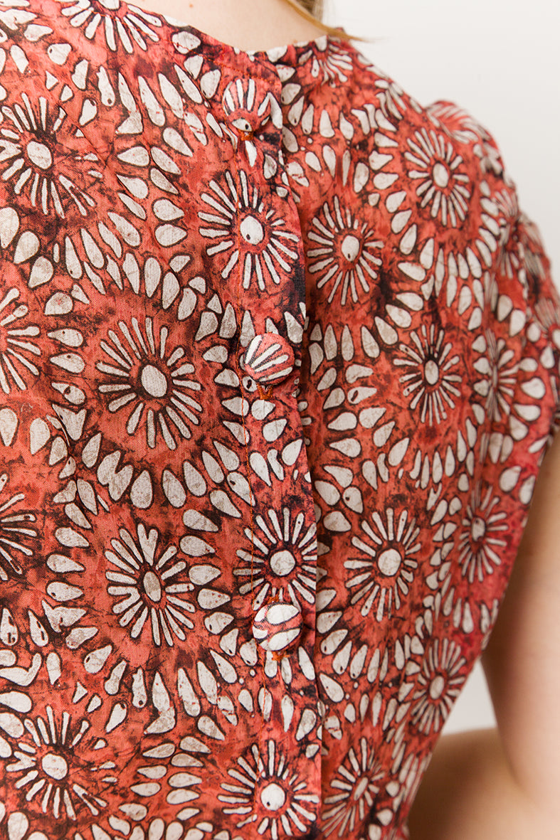 Model in red light cotton top with flowers- detail on hand crafted buttons